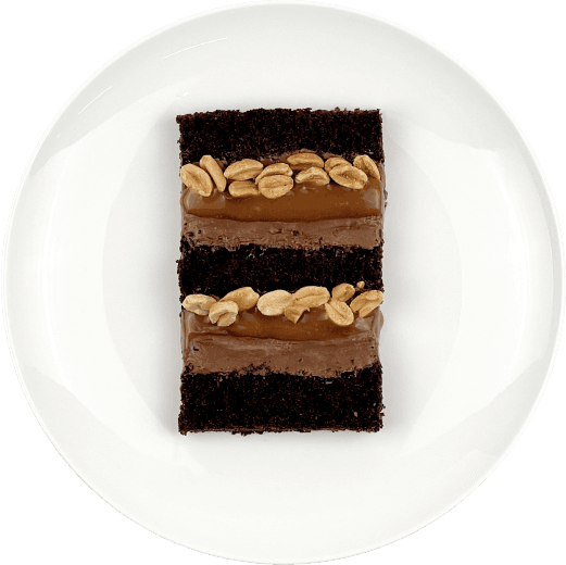 Шматочок торту з двошаровою шоколадно-карамельною начинкою на тарілці.