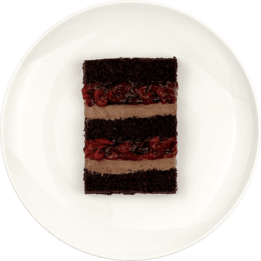 Шматочок торту з двошаровою начинкою вишня-єгермейстер на тарілці.